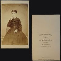 Antique CDV Carte De Visite: Woman from the ankle area up, finger to her cheek wearing a dark, flowing dress: Front and Back View - Click to enlarge