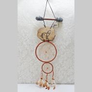 Dream Catcher with image of a howling wolf imprinted on a rock hanging from a stick and two webbed hoops. Feathers and beads: Front View