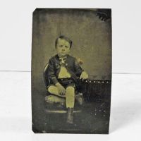 Antique Tintype Photo: Bored boy with a blank stare sitting in a chair with his legs crossed: Front View - Click to enlarge