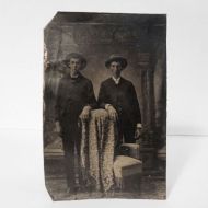 Antique Tintype Photo: Two men wearing big hats standing side by side, one arm resting on a blanket covered chair: Front View