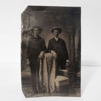 Antique Tintype Photo: Two men wearing big hats standing side by side, one arm resting on a blanket covered chair: Front View - Click to enlarge