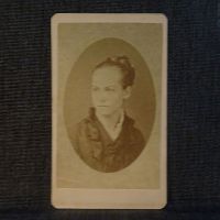 Antique CDV Carte De Visite: Woman from the shoulder area up with a braided bun, straight line smile and ruffled collar: Front View - Click to enlarge