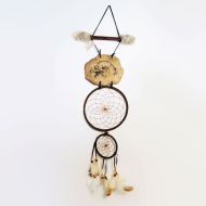 Dream Catcher with image of an eagle head imprinted on a rock hanging from a stick and webbed hoops. Feathers and beads: Front View