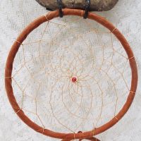 Dream Catcher with image of a howling wolf imprinted on a rock hanging from a stick and two webbed hoops. Feathers and beads: Center Dream Catcher View - Click to enlarge