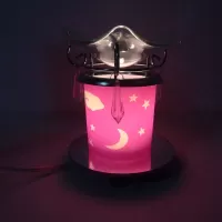 Electric oil warmer featuring a pink night sky of white stars, moon and clouds mounted on a round mirror base: Turned On - Click to enlarge