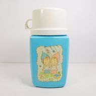 1975 Precious Moments 8 oz. thermos with blue plastic body and cream colored top that doubles as a cup: Front View