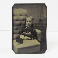 Antique Tintype Photo: Smiling little girl sitting in a too big buttoned back chair: Front View - Click to enlarge