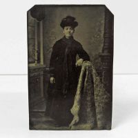 Antique Tintype Photo: Woman standing, leaning her arm on something draped with a blanket wearing a fancy hat: Front View - Click to enlarge