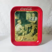 Vintage 1987 Coca Cola metal tray wall hanging shows a blacksmith and boy drinking coke from a bottle: Front View - Click to enlarge